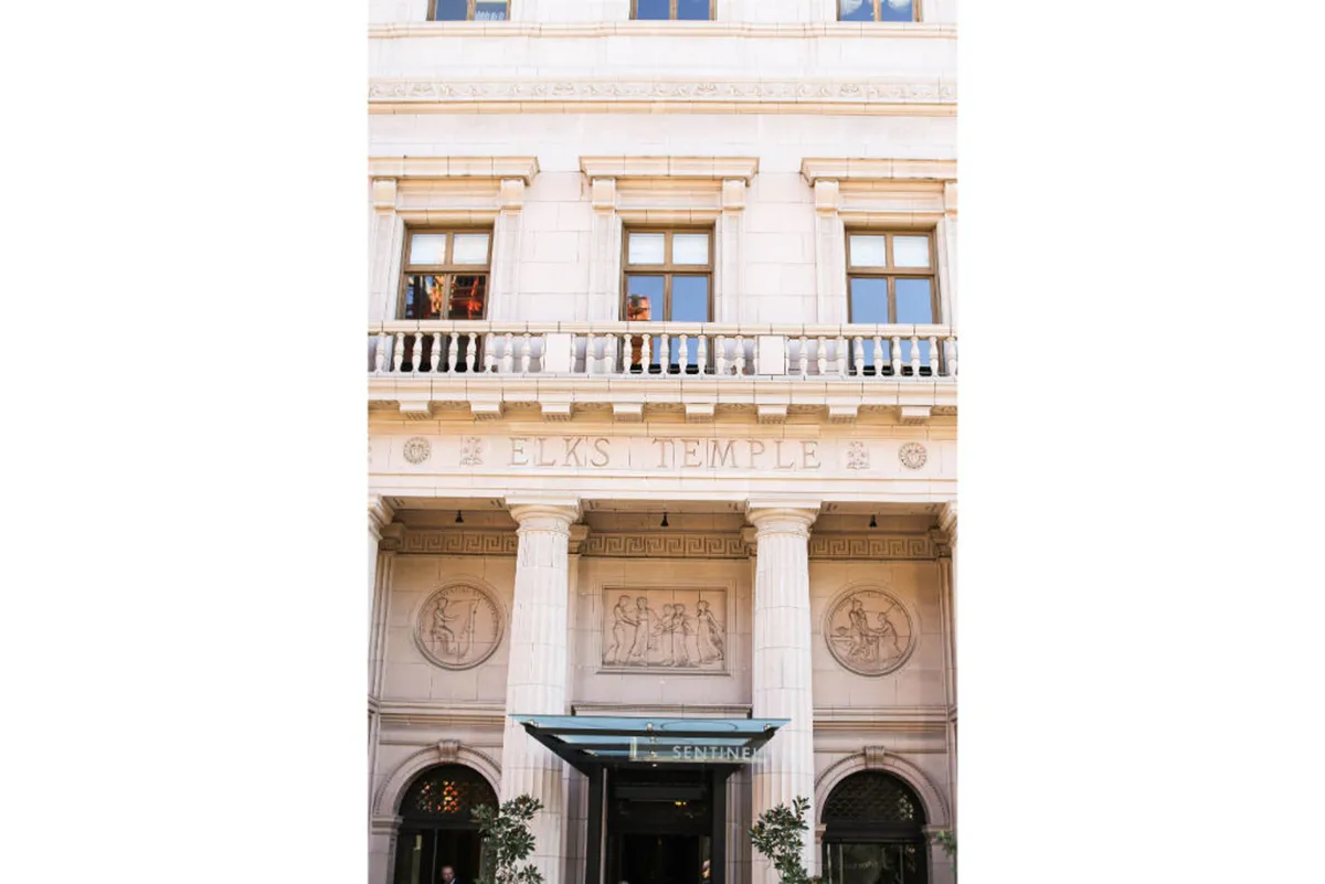 The exterior of the iconic Elks Temple, featuring prominent signage, decorative columns, and detailed facade work. It suggests historical significance and is often a focal point for cultural events and photography in the West End.